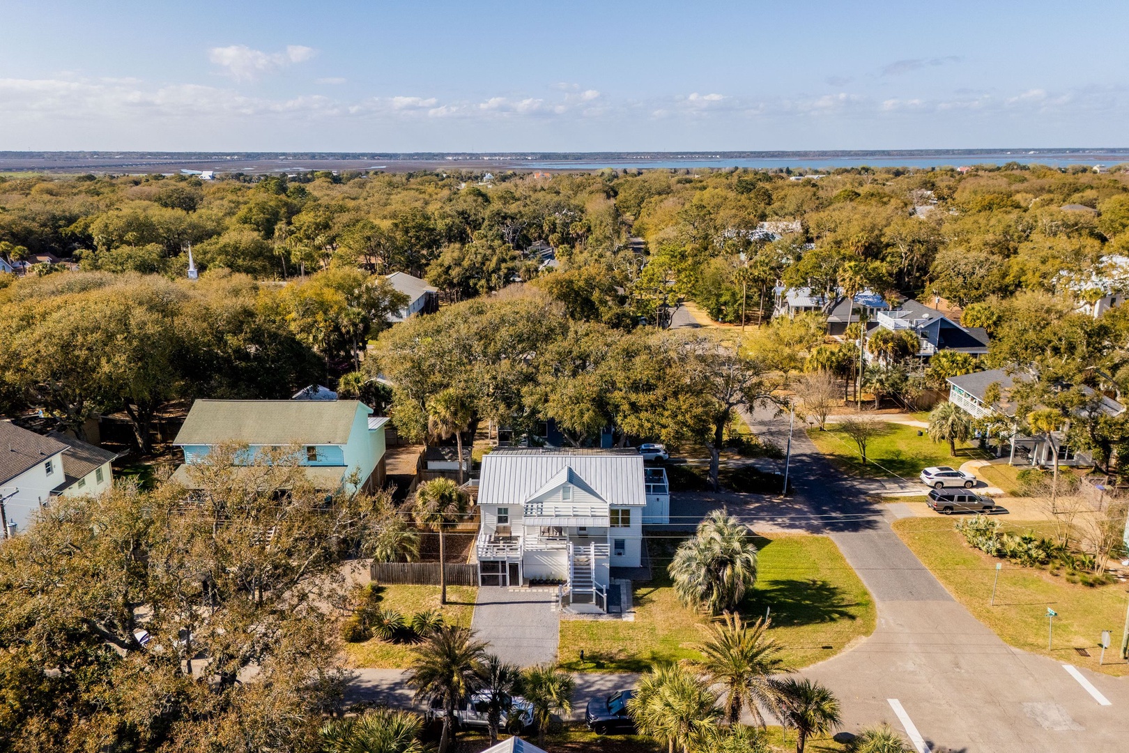 Aerial view of a coastal neighborhood with tree-lined streets and nearby ocean access, showcasing the peaceful residential setting.