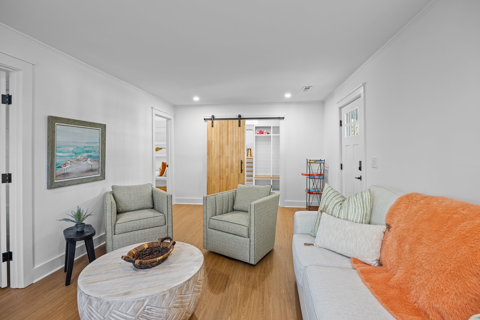 Sink into plush seating in your bright, modern living room where coastal artwork and warm wood tones create the perfect retreat for relaxation.