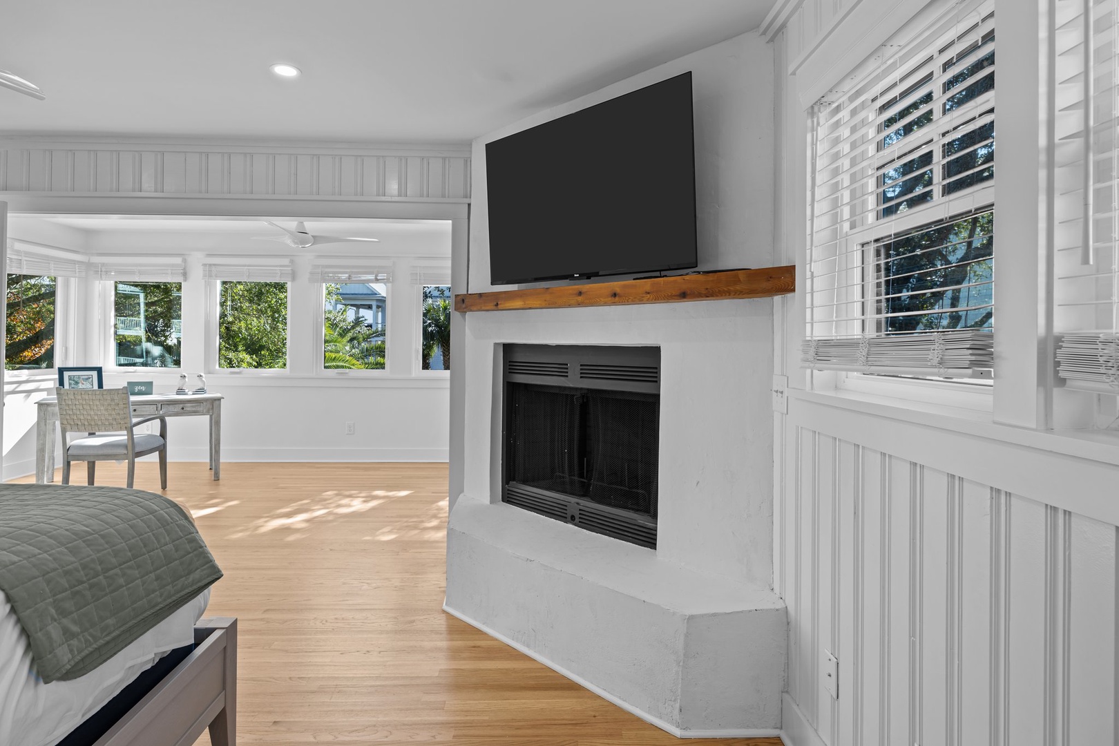 Cozy up by your personal fireplace while watching TV, with sunny views streaming through pristine white shutters in this bright, airy space.