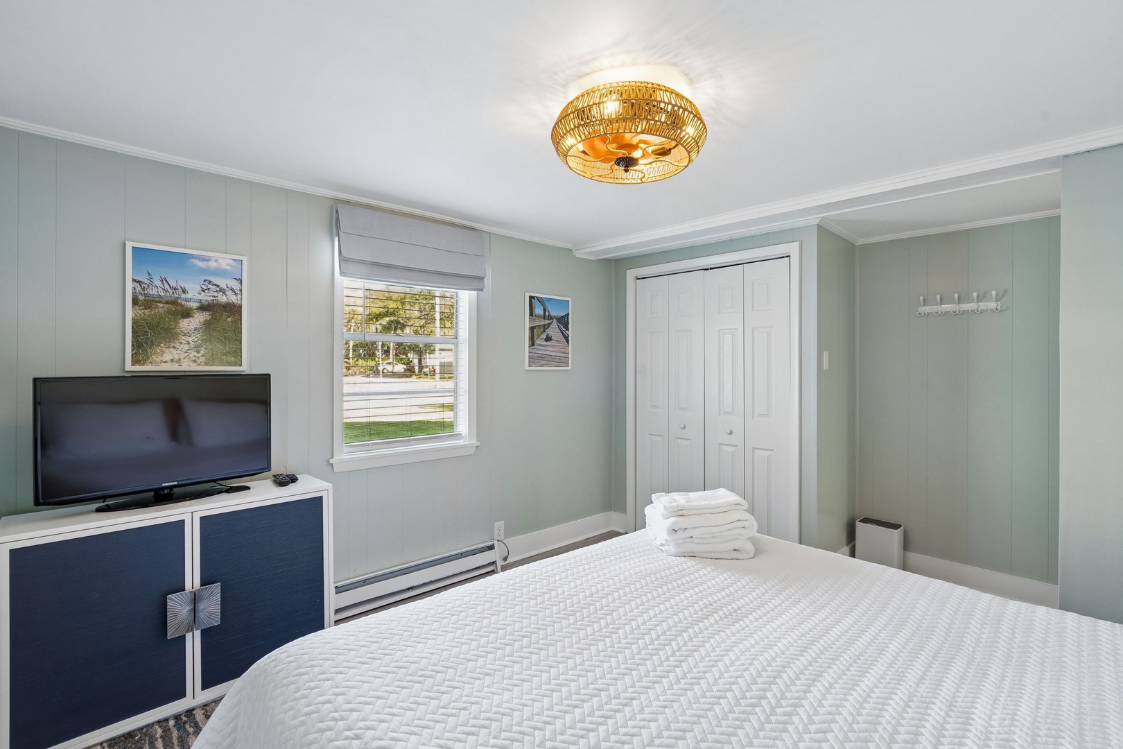 Relax in your peaceful bedroom with calming coastal vibes, soft linens, and a warm wicker ceiling light creating the perfect retreat.