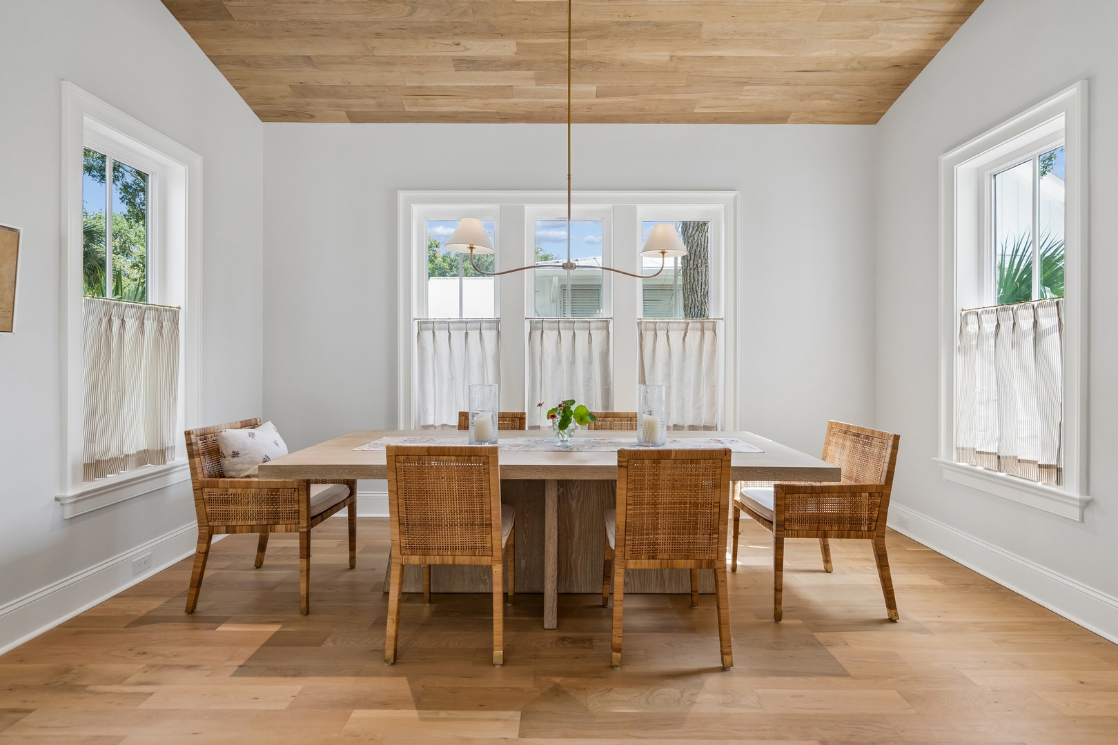 Gather around the warm wood table beneath a charming wood-plank ceiling, where bright natural light and coastal breezes flow through three large windows. This inviting dining space sets the perfect scene for memorable meals with loved ones.
