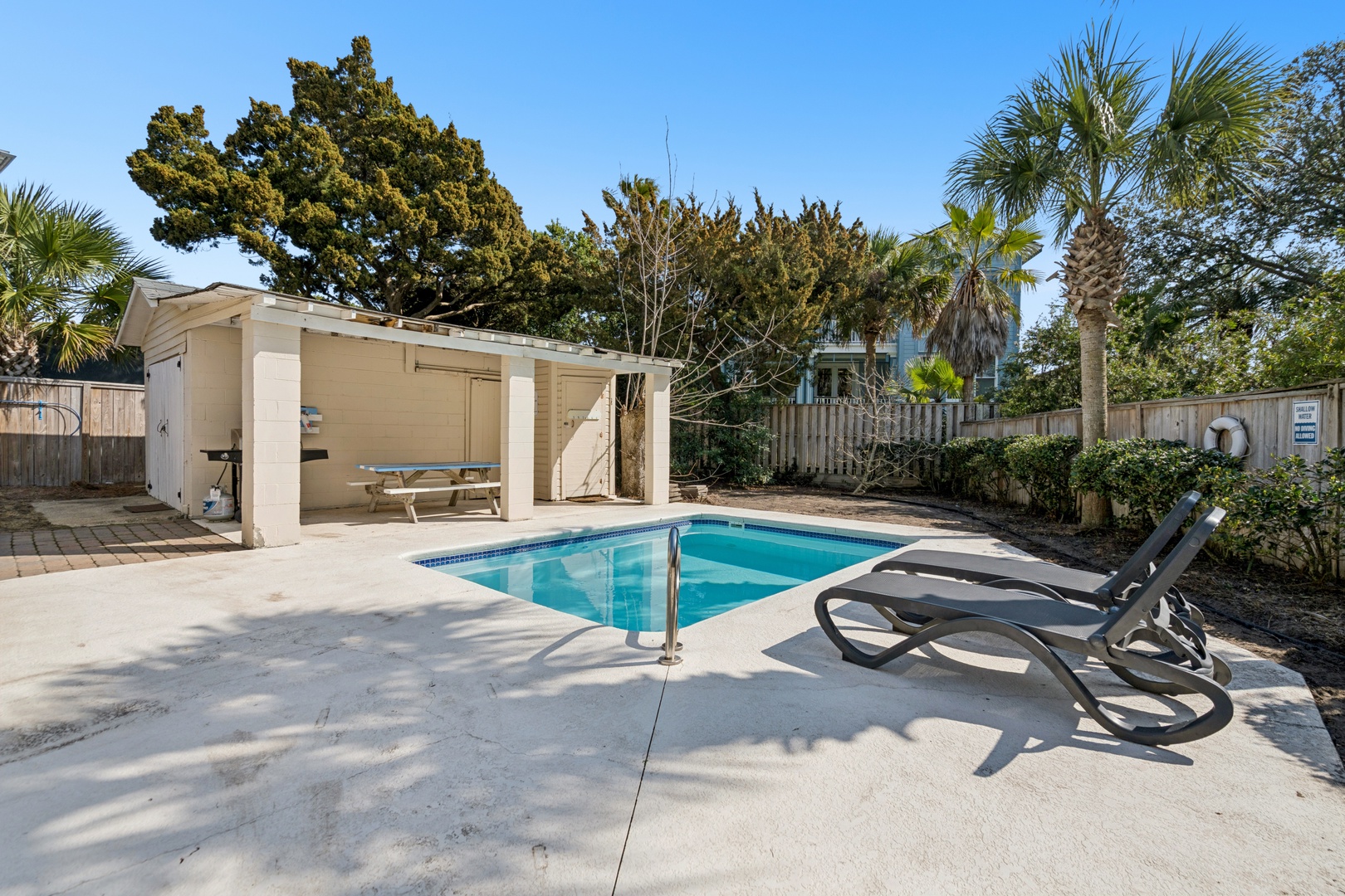 Your private oasis awaits with a sparkling pool surrounded by tropical palms, poolside loungers for soaking up sunshine, and covered outdoor dining.