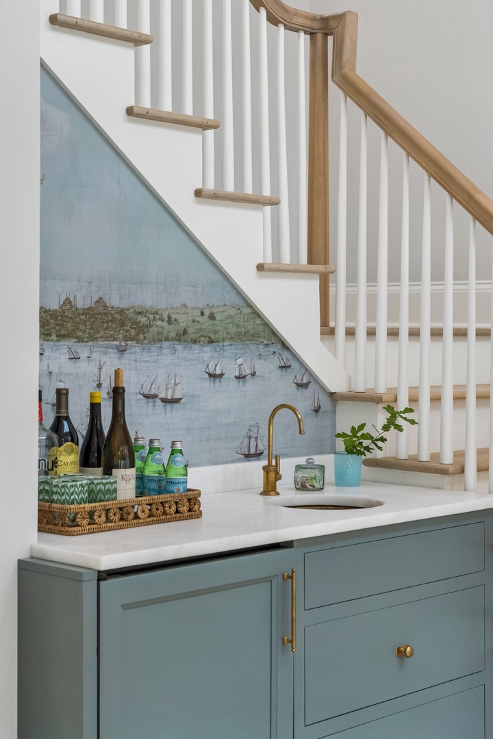 Tucked beneath the staircase, your private wet bar invites easy entertaining with coastal-inspired cabinetry and gleaming fixtures ready for your favorite refreshments.