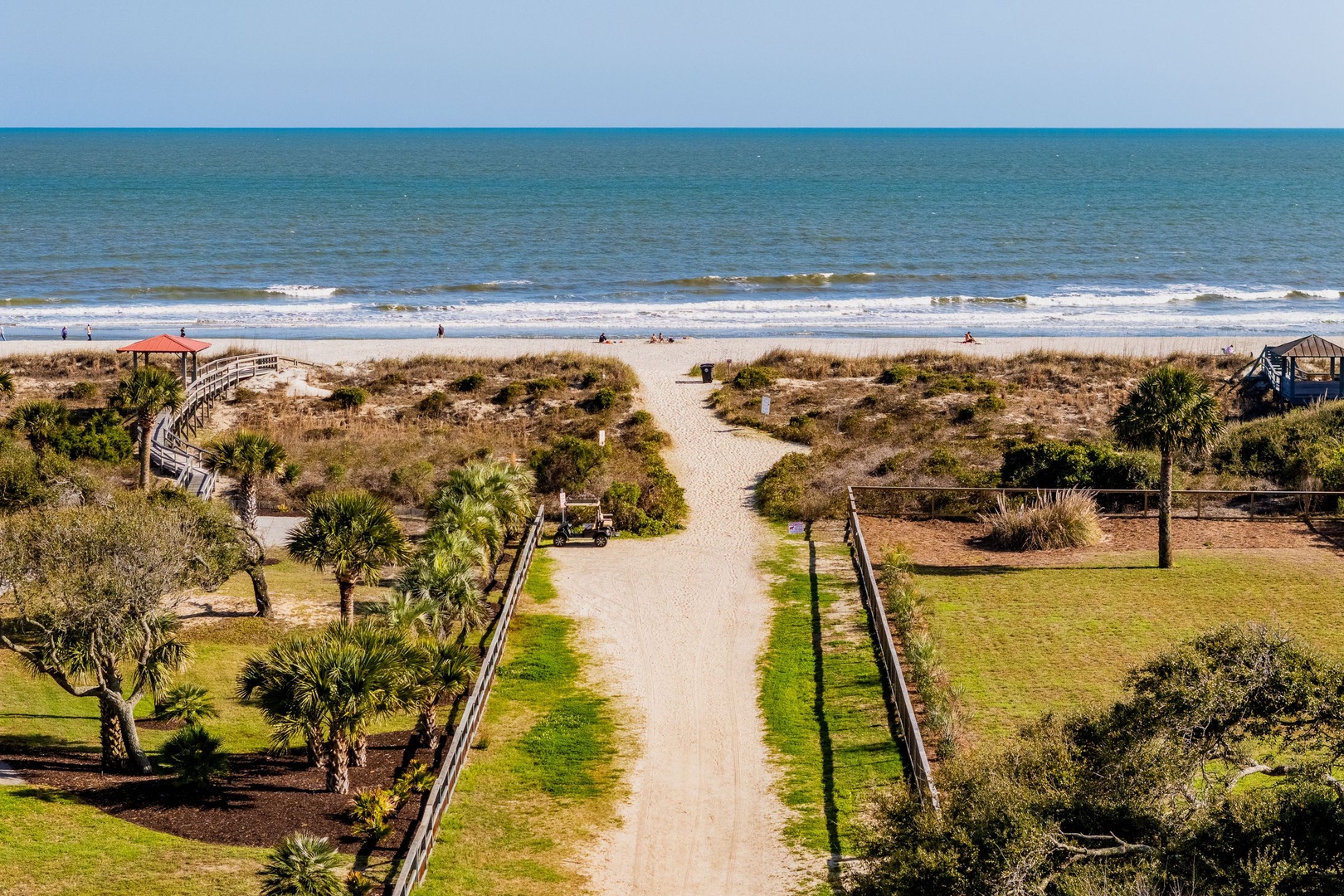 Pristine oceanfront location with direct beach access path leading to sandy shores and gentle waves.