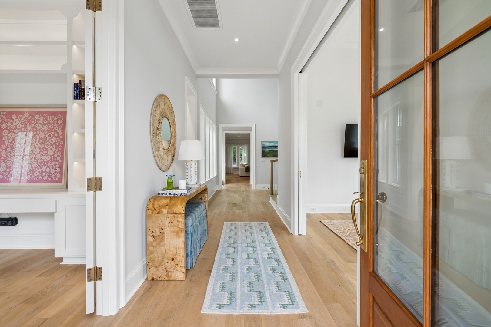 Step into this bright, welcoming hallway where warm wood floors guide you through the home. Natural light and elegant details create a serene, airy atmosphere perfect for your getaway.