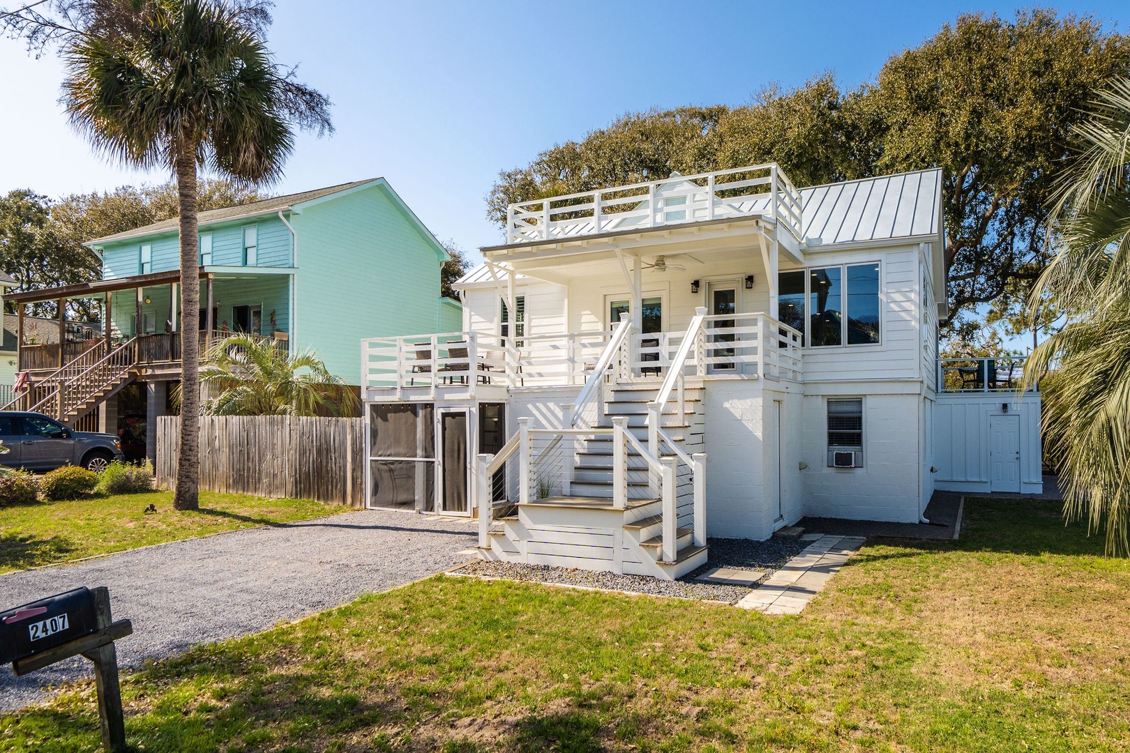 Charming coastal cottage with elevated deck and tropical palms creates the perfect beach getaway atmosphere.