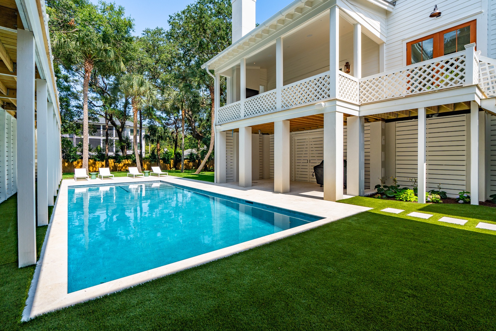 A pristine swimming pool framed by lush greenery and elegant two-story porches invites you to relax in your own private backyard oasis.