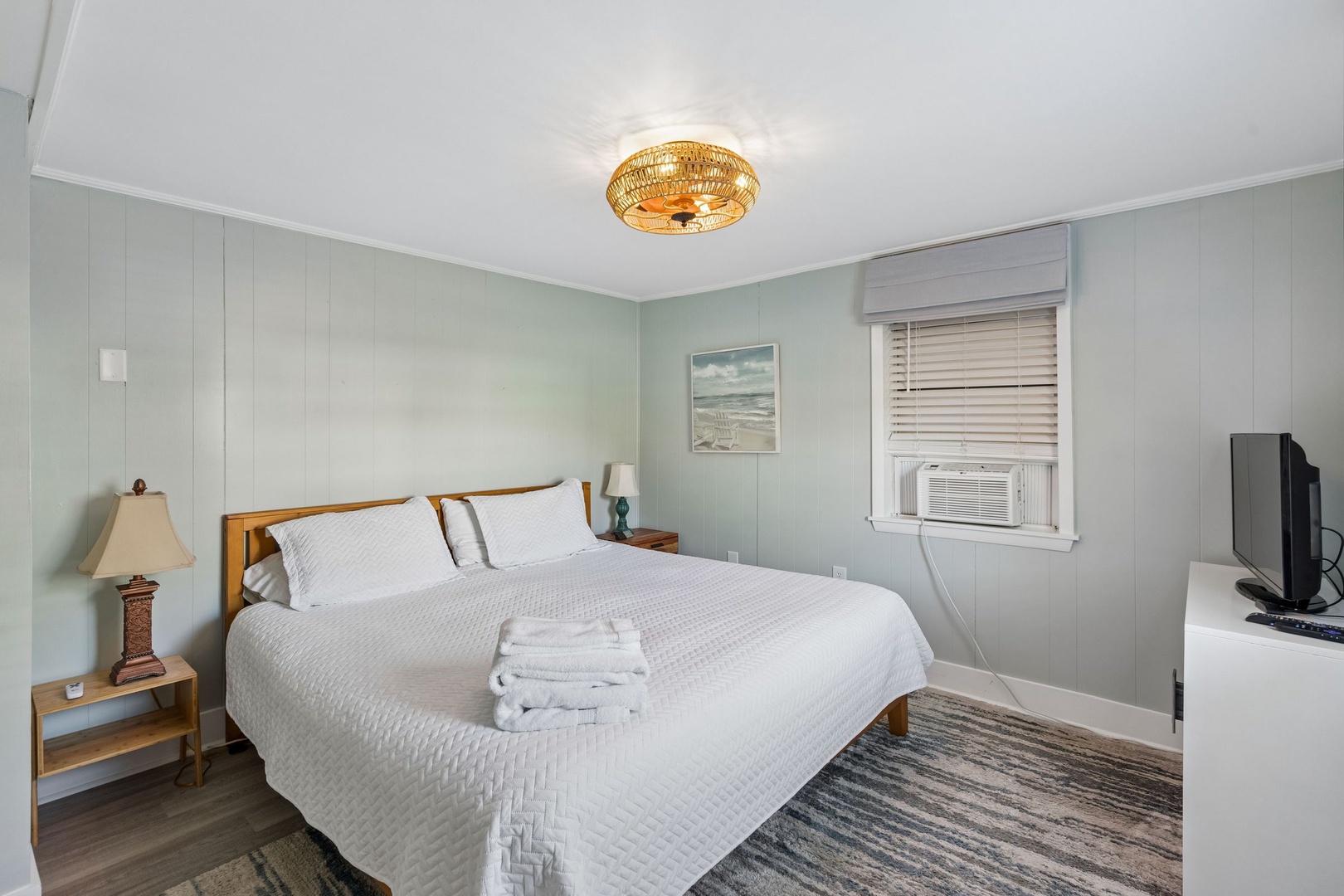 Your peaceful bedroom features crisp linens, a unique woven ceiling light, and comfy seating area for relaxing after beach days.