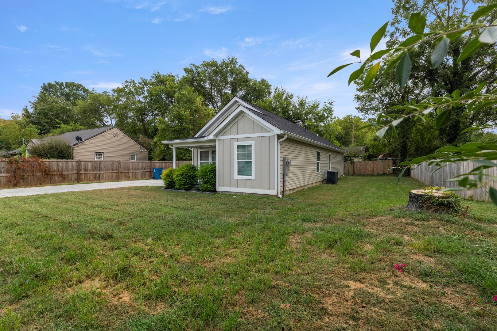 The property sits on a peaceful residential street, surrounded by mature trees and a spacious grassy yard with a wood-fenced backyard offering privacy.