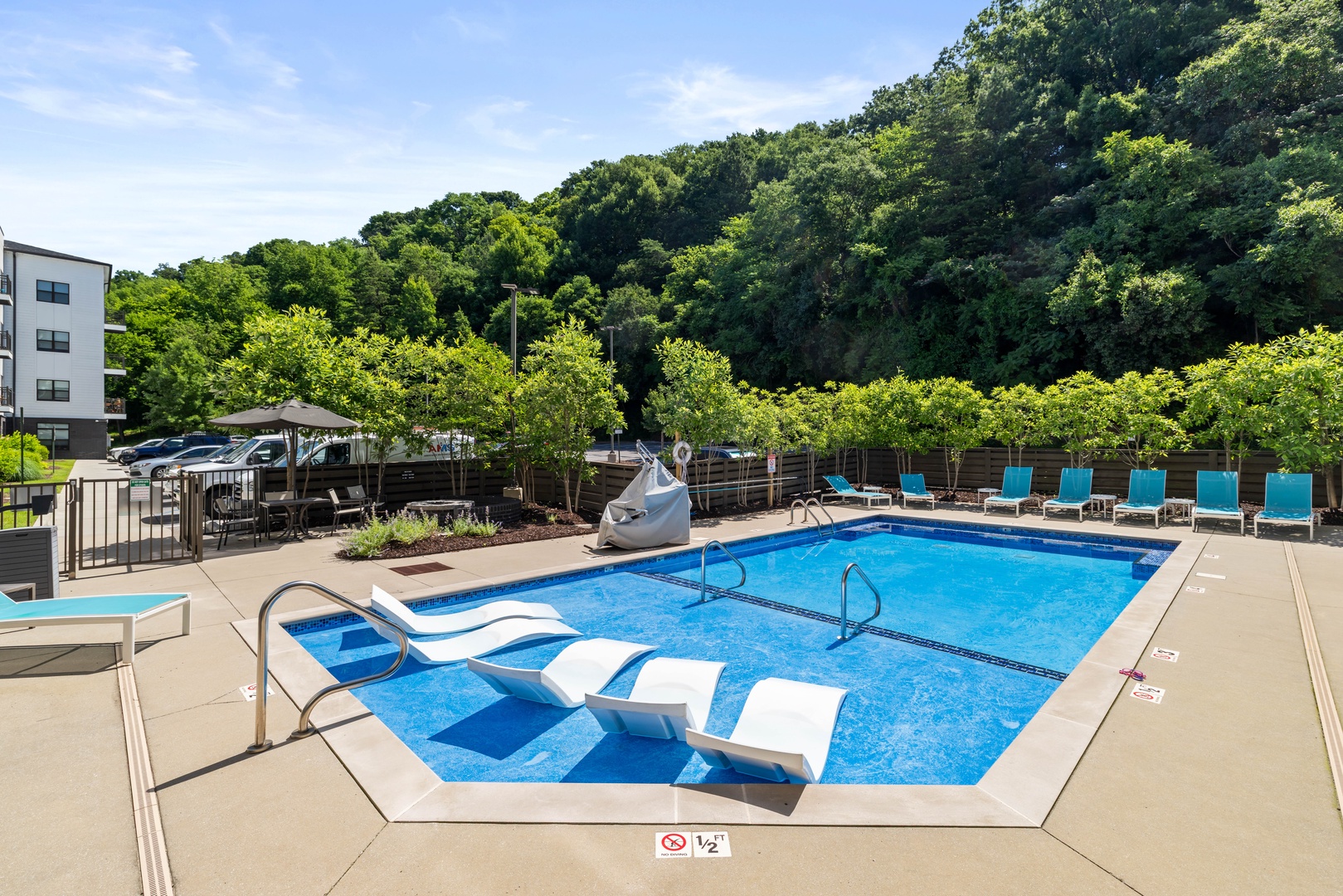 Surrounded by lush greenery and framed by nearby buildings, the pool area offers a private, relaxing atmosphere that feels tucked away from it all while still being just steps from your stay.