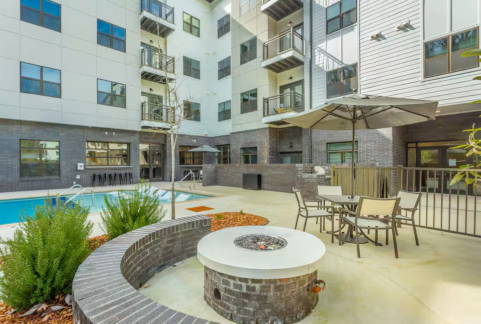 Modern complex features an inviting courtyard with fire pit seating, pool, and outdoor dining areas surrounded by contemporary architecture.