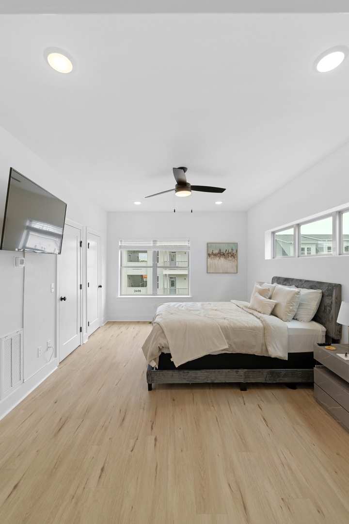 Settle into the inviting primary bedroom, featuring a comfortable queen bed for a restful night’s sleep wood floors, and soothing natural light that creates the perfect sanctuary for rest and relaxation.
