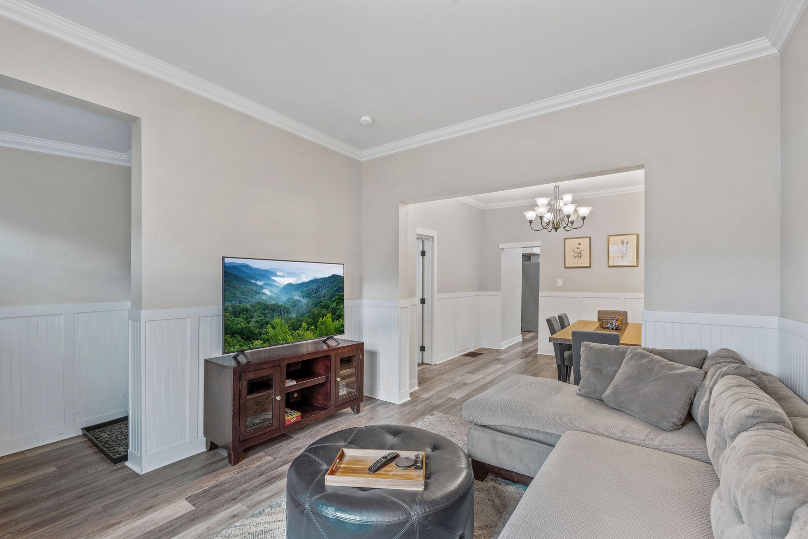 Unwind in your spacious living room featuring plush seating, a large smart TV, and beautiful hardwood floors that connect to your dining area.