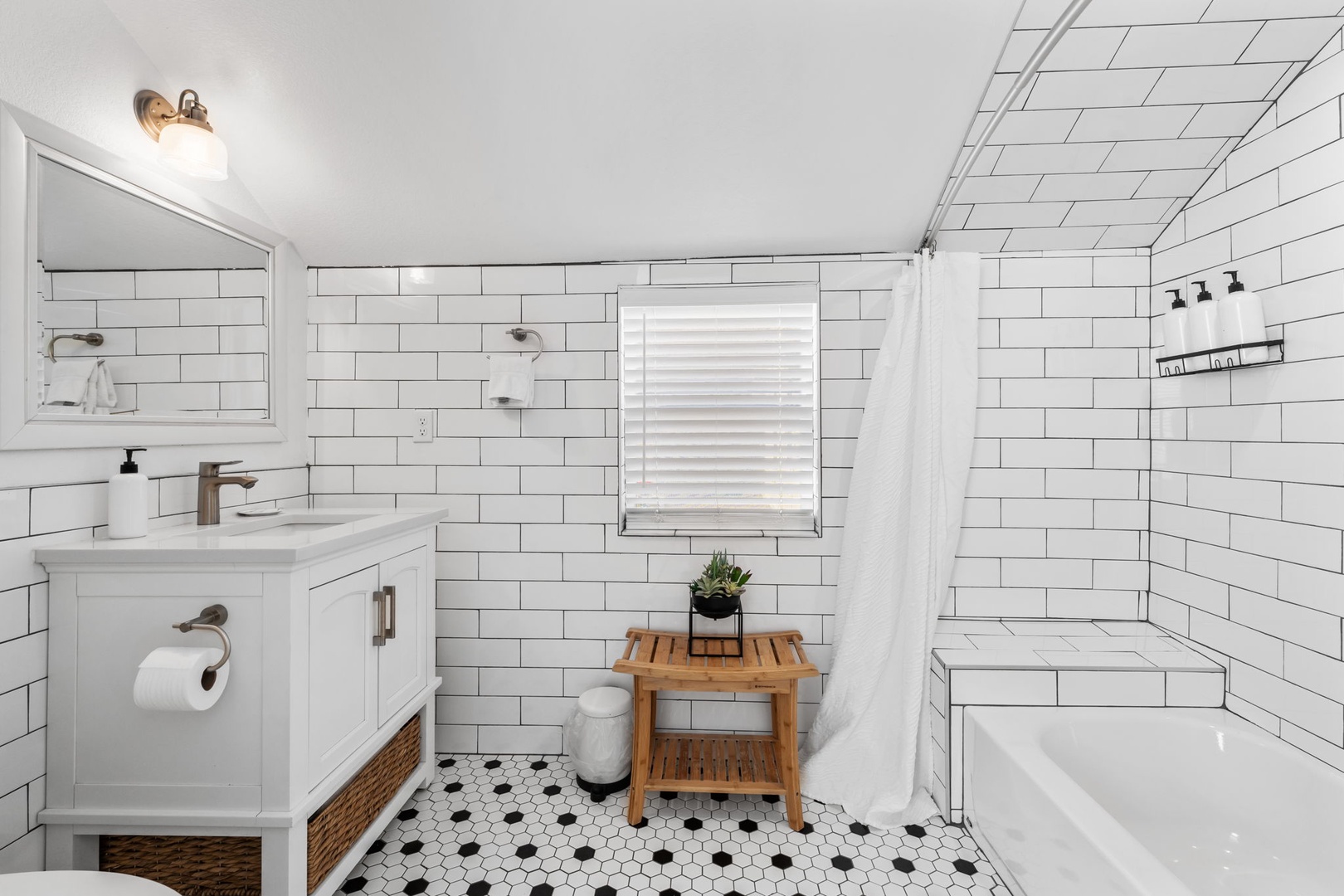 Unwind in your pristine bathroom featuring classic subway tiles, a soaking tub, and thoughtful touches like a bamboo stool.