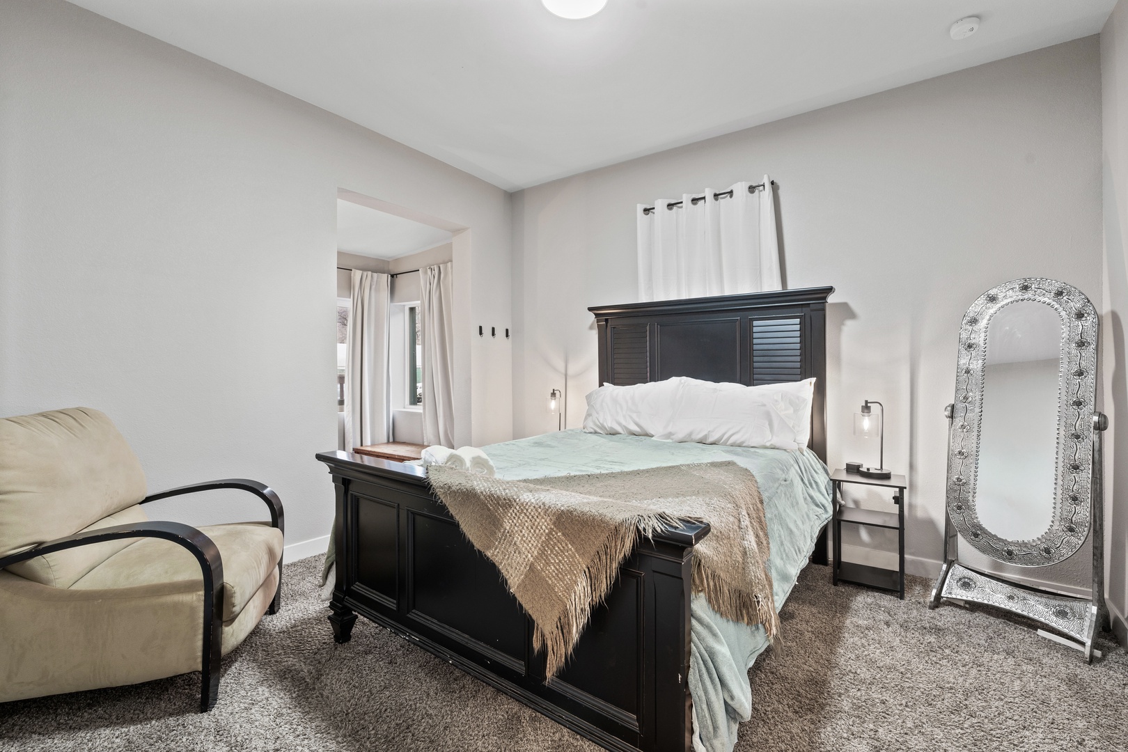 Relax in your elegantly appointed bedroom featuring a comfortable bed, cozy reading chair, and full-length mirror - perfect for unwinding after a day of exploring.