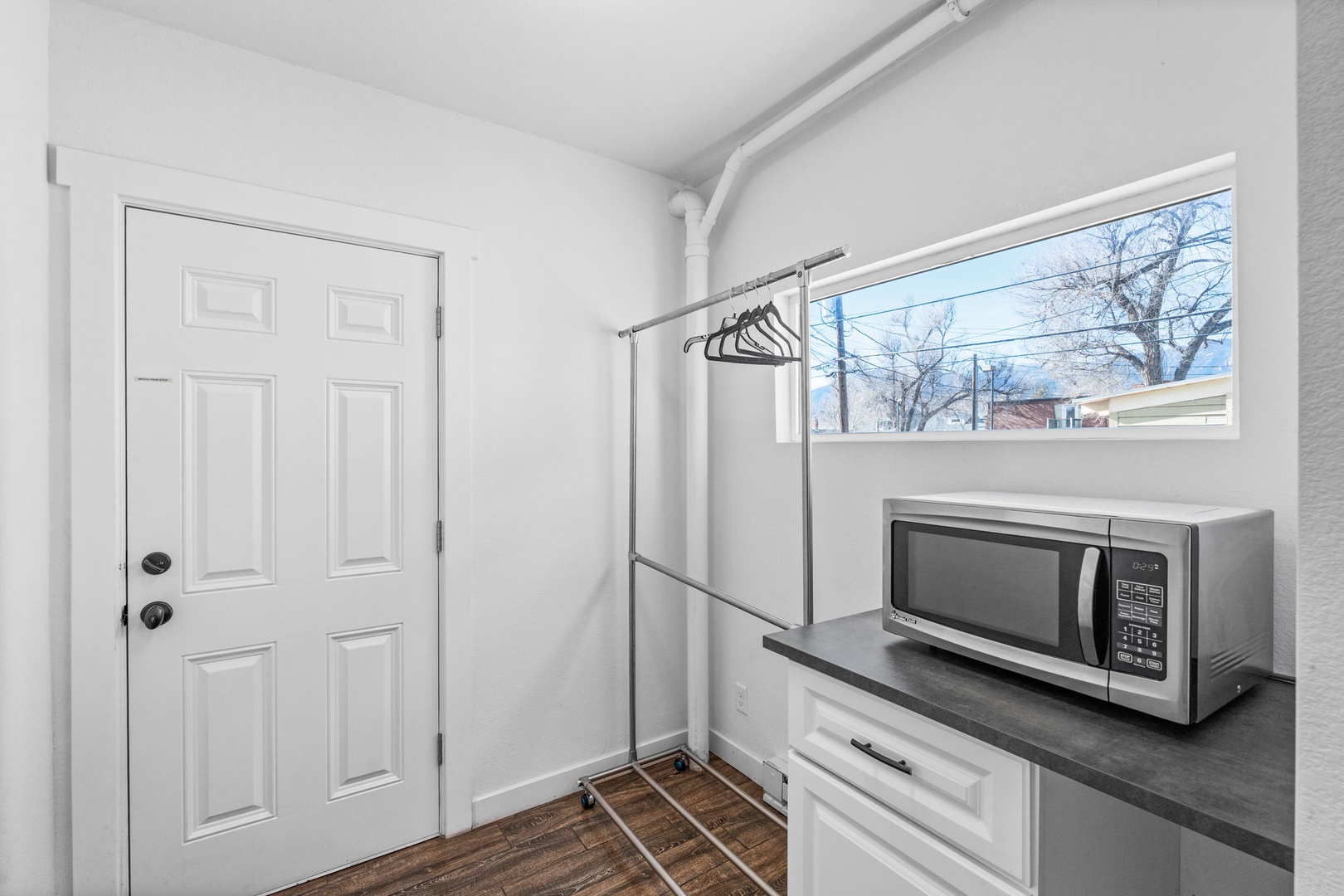 Your bright laundry area features a convenient microwave, hanging space for clothes, and natural light from windows overlooking the neighborhood.