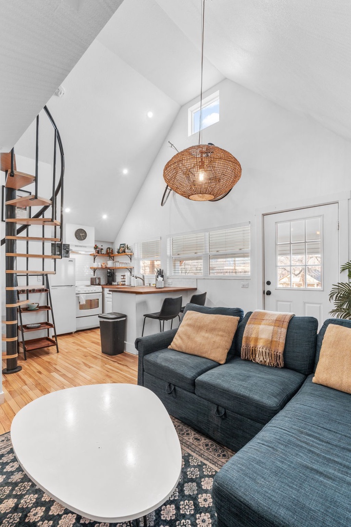 Relax in your bright loft with soaring ceilings, cozy blue sofa, and warm wood accents creating the perfect retreat.