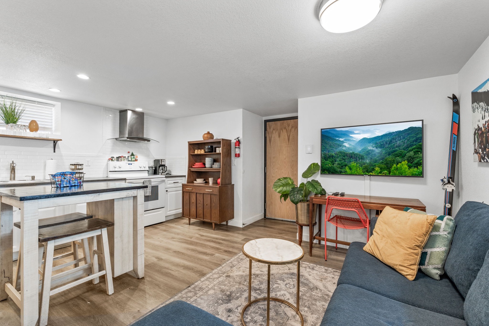 Your modern open-concept space seamlessly blends living and kitchen areas, featuring sleek appliances, cozy seating, and a large TV for relaxation.