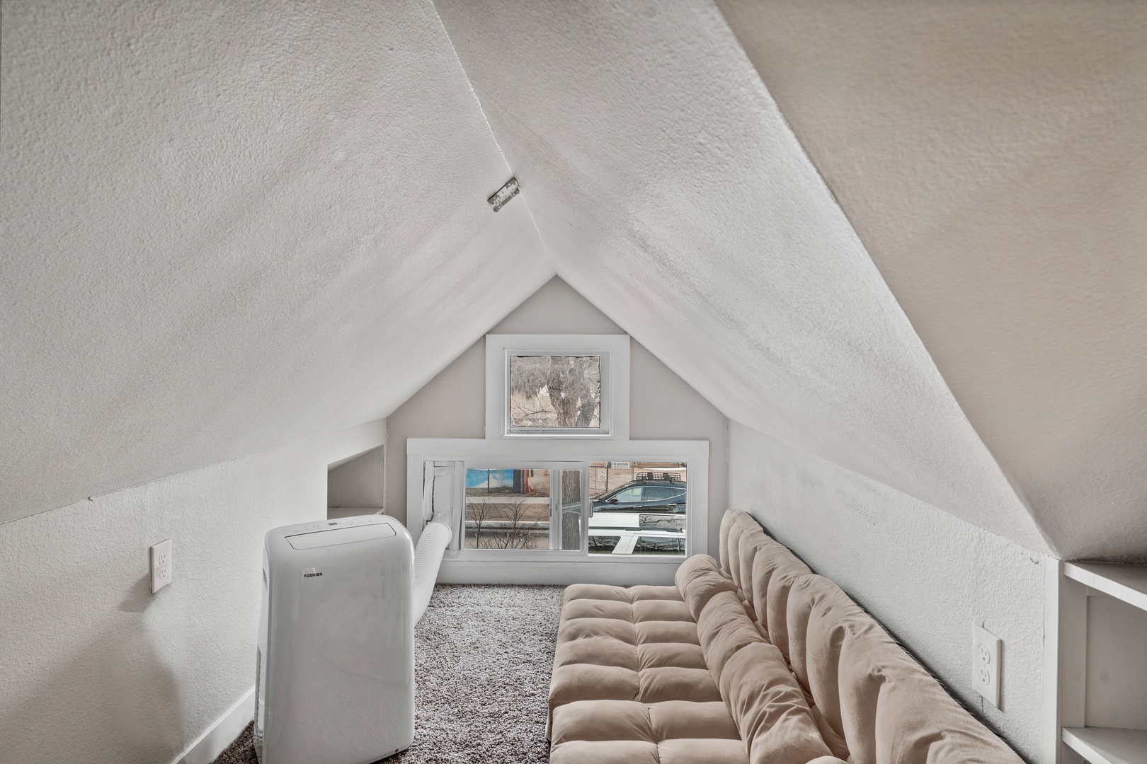 Cozy attic lounge with slanted ceilings, plush seating, and natural light - your perfect retreat for relaxation.