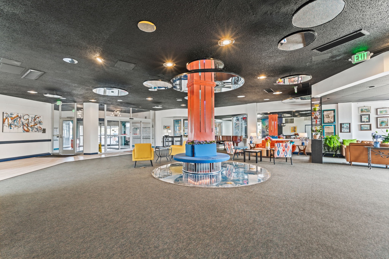 A striking property lobby featuring bold orange columns, modern circular seating, and vibrant accent chairs—welcoming space blending contemporary design with artistic flair throughout.