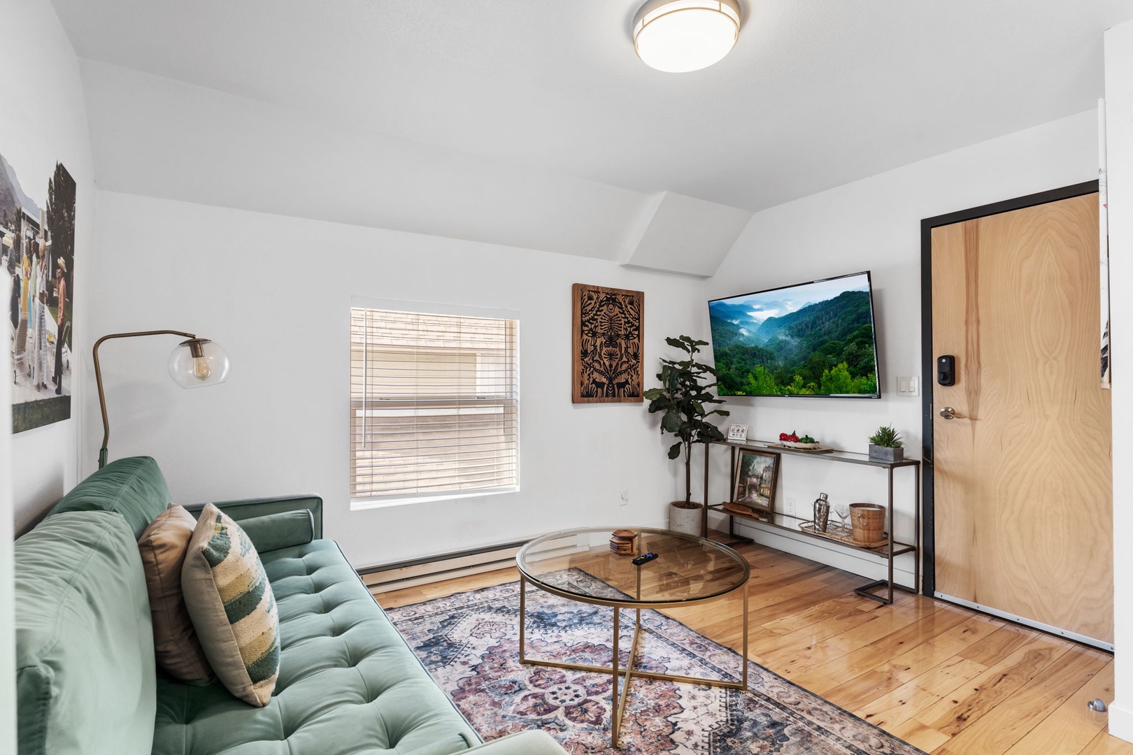 Unwind in your stylish living room, featuring a plush emerald sofa and warm wood floors that invite relaxation.