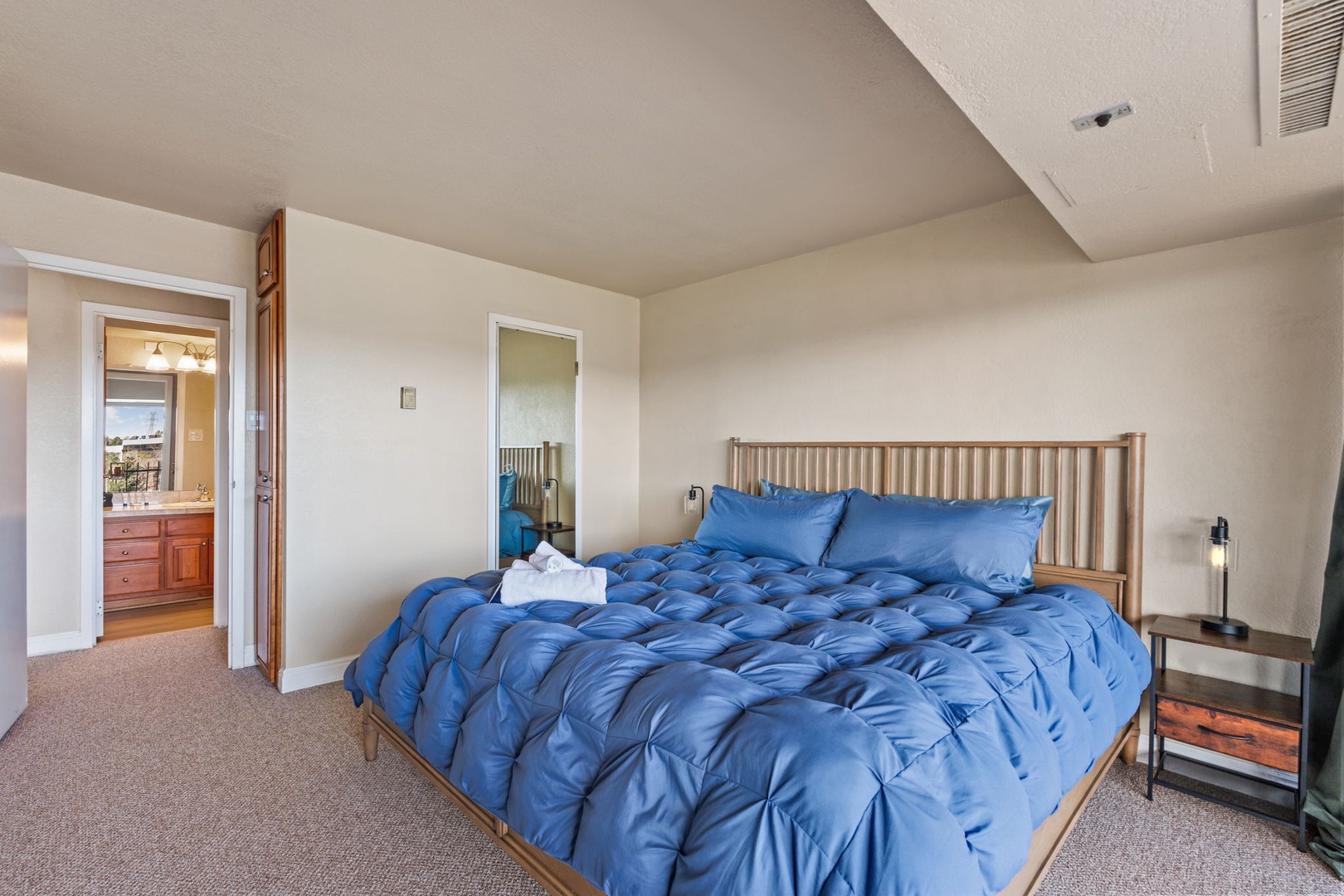 Your serene bedroom retreat awaits, with plush blue bedding and soft carpeting underfoot. Modern touches and an en-suite bath promise comfort after a day exploring.