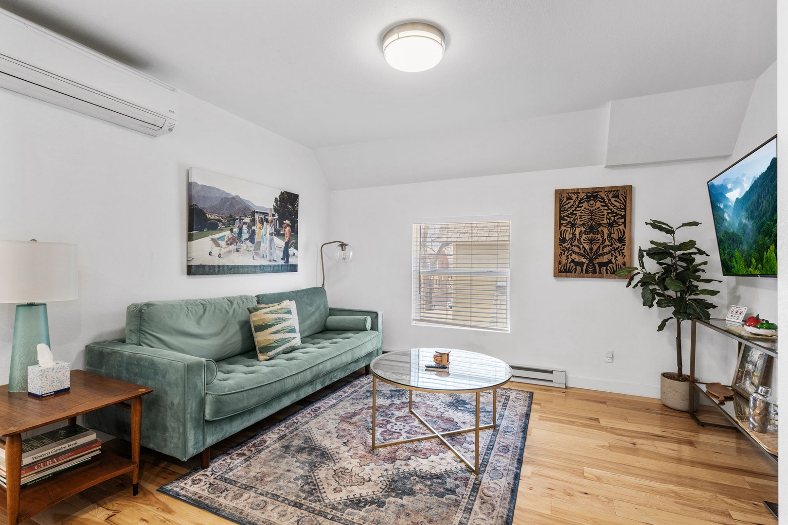 Relax in your stylish living room with plush green sofa, curated artwork, and warm wood floors creating the perfect retreat.