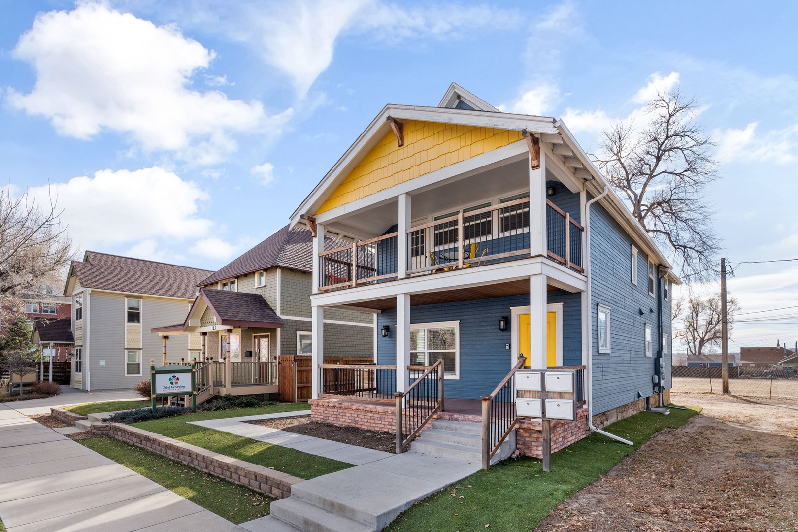 Modern two-story duplex with covered balcony and welcoming front porch in a quiet residential neighborhood.