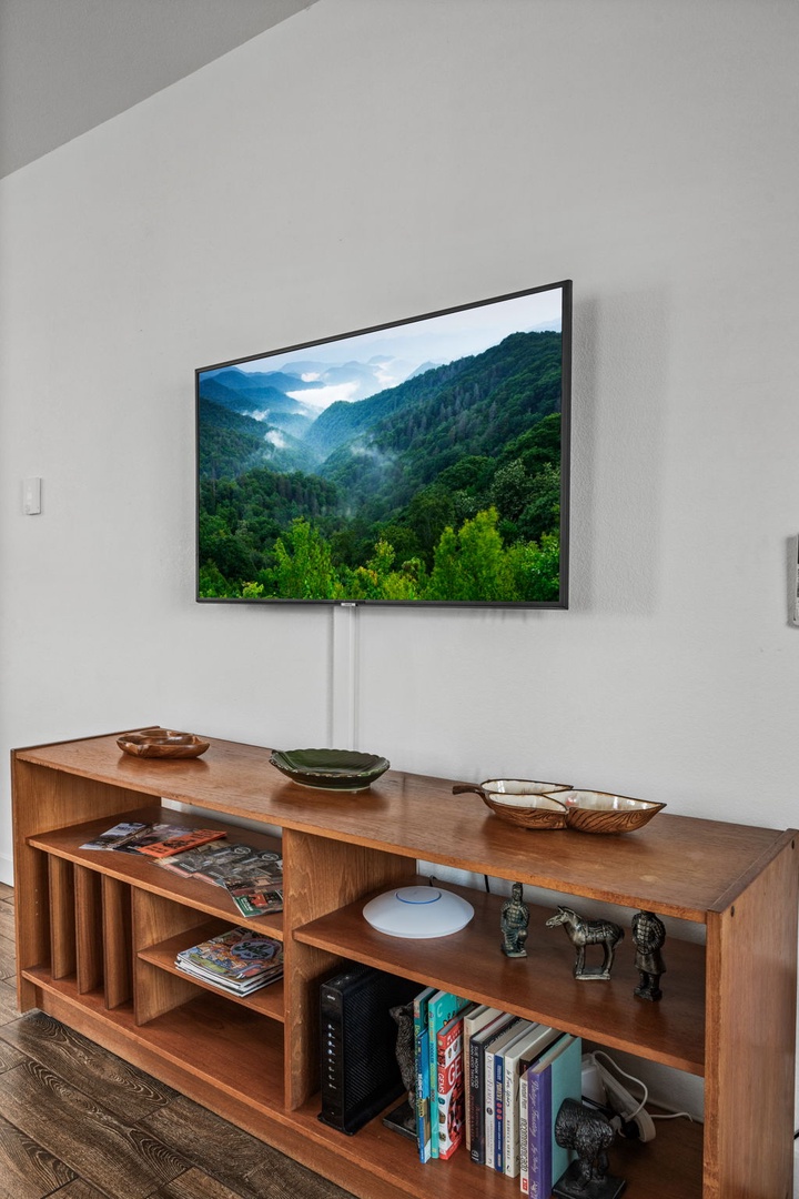 Unwind in your cozy living space with a flat-screen TV and warm wood console filled with books and thoughtful touches.