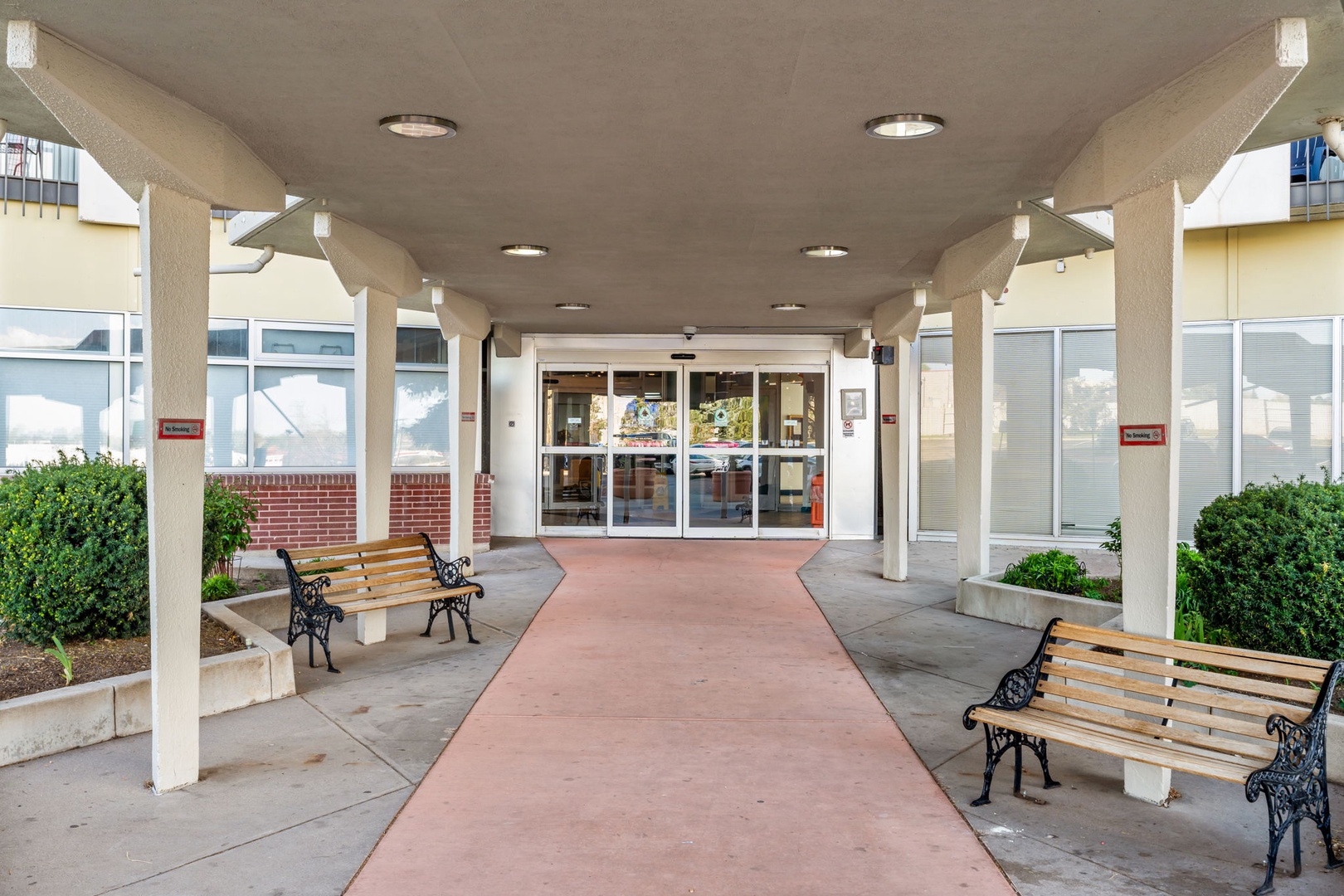 The property entrance features a covered walkway with decorative benches and landscaped greenery, providing a welcoming arrival experience.