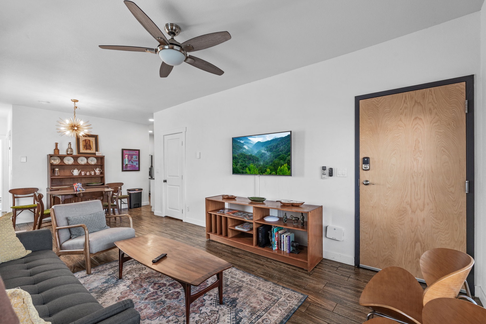 Relax in your stylish living space with mid-century furniture, ceiling fan, and entertainment center for cozy evenings.