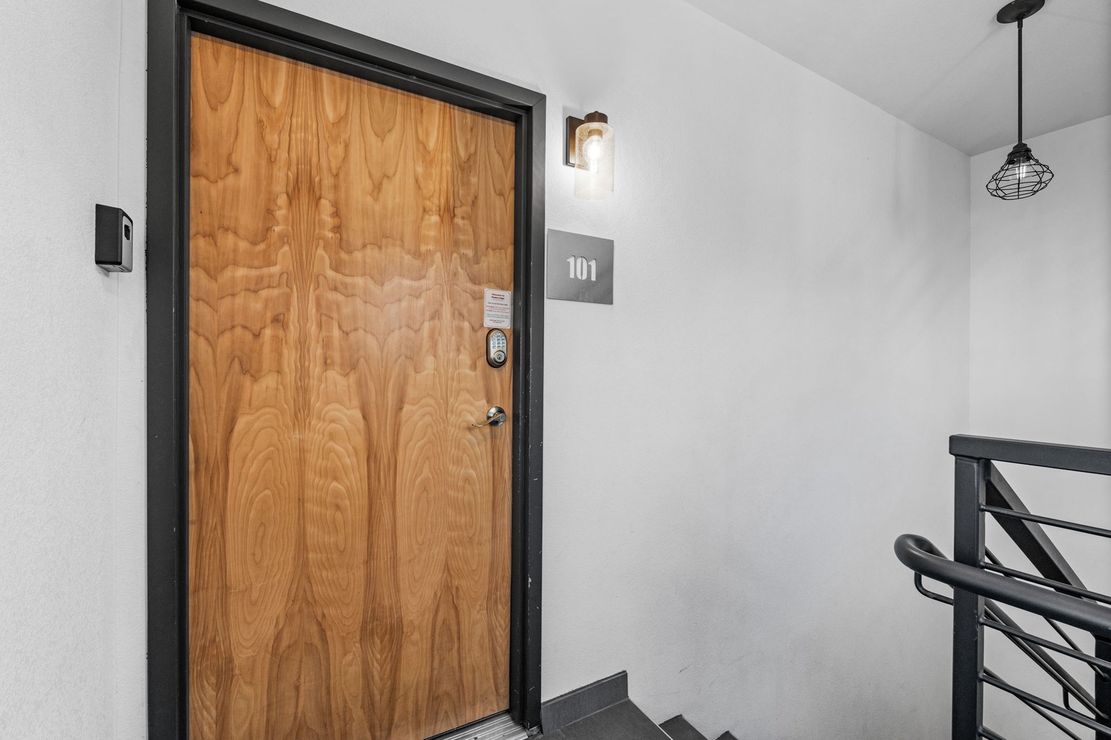 Modern entrance to room 101 with warm wood door and sleek industrial lighting creates a welcoming first impression.