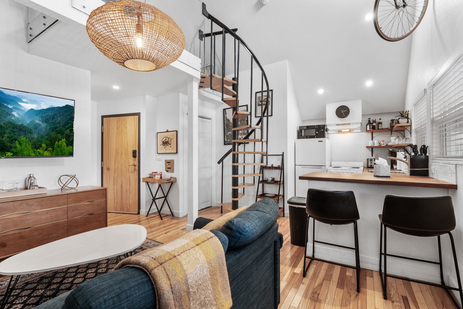 Your stylish open-plan retreat features modern kitchen, cozy seating, and spiral stairs to your private loft space above.