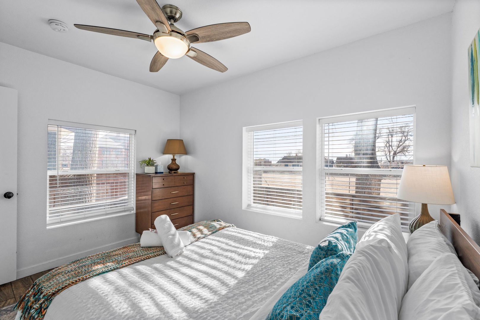 Wake up refreshed in this bright bedroom where natural light streams through large windows and a gentle ceiling fan keeps you comfortable all night.