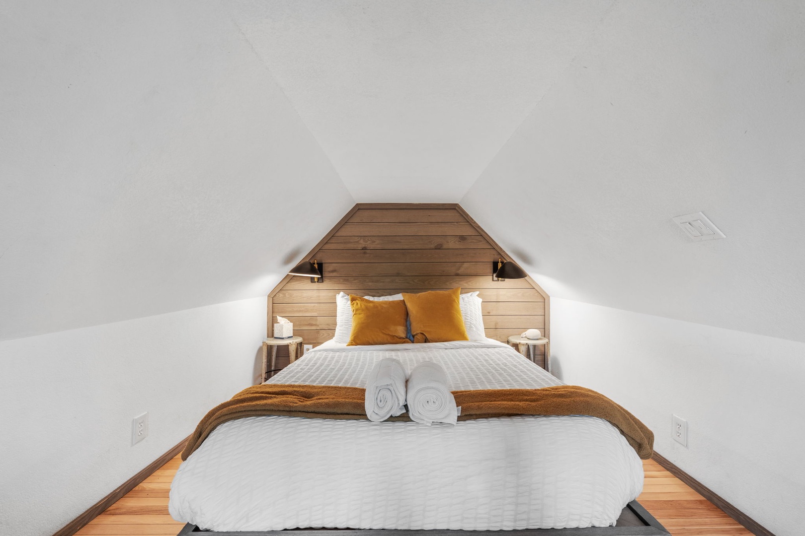 Drift off in this cozy loft bedroom with its warm wood accents and plush bedding, where soft lighting creates the perfect retreat.