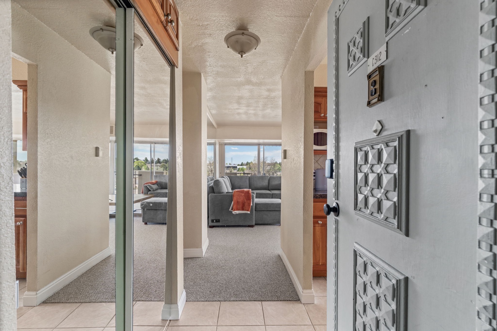 Step into your inviting hallway where natural light spills through expansive windows, drawing you toward the comfortable living area and stunning city views beyond.