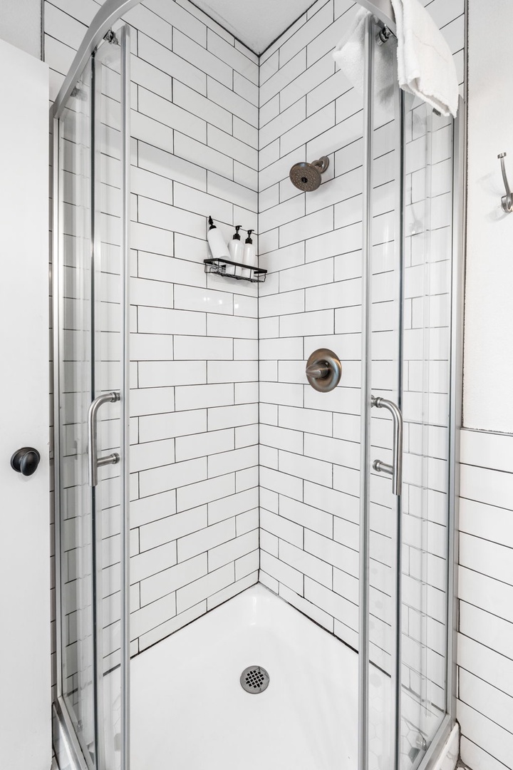 Step into your pristine glass-enclosed shower with classic white subway tiles and modern bronze fixtures for a refreshing start to your day.