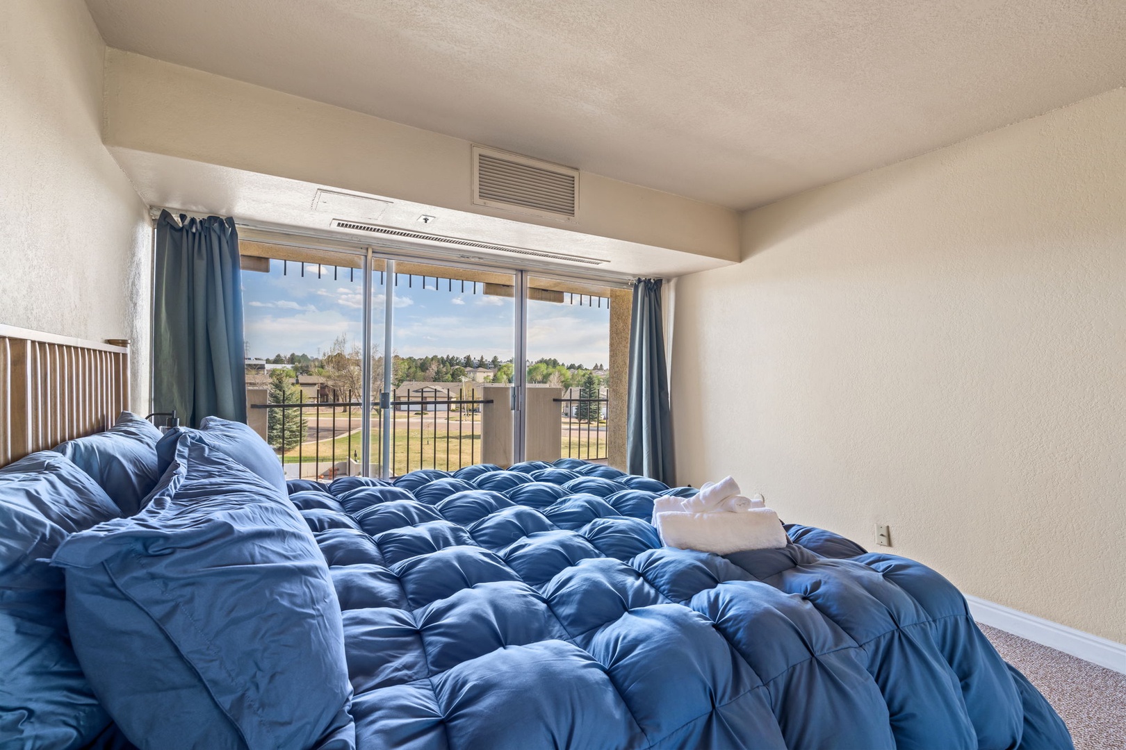 Wake up in this sun-filled bedroom where plush blue bedding and peaceful views create your perfect morning retreat. Natural light pours through sliding glass doors leading to your private balcony.