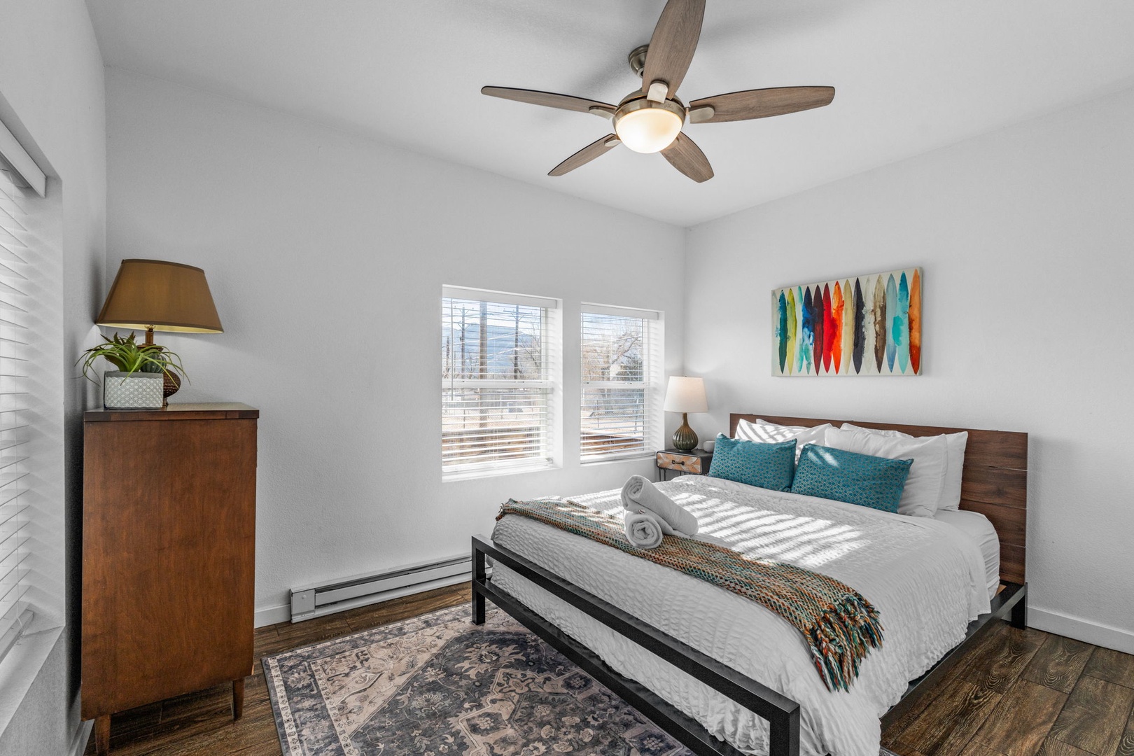 Unwind in your serene bedroom featuring fresh linens, modern furnishings, and colorful art that creates the perfect retreat.