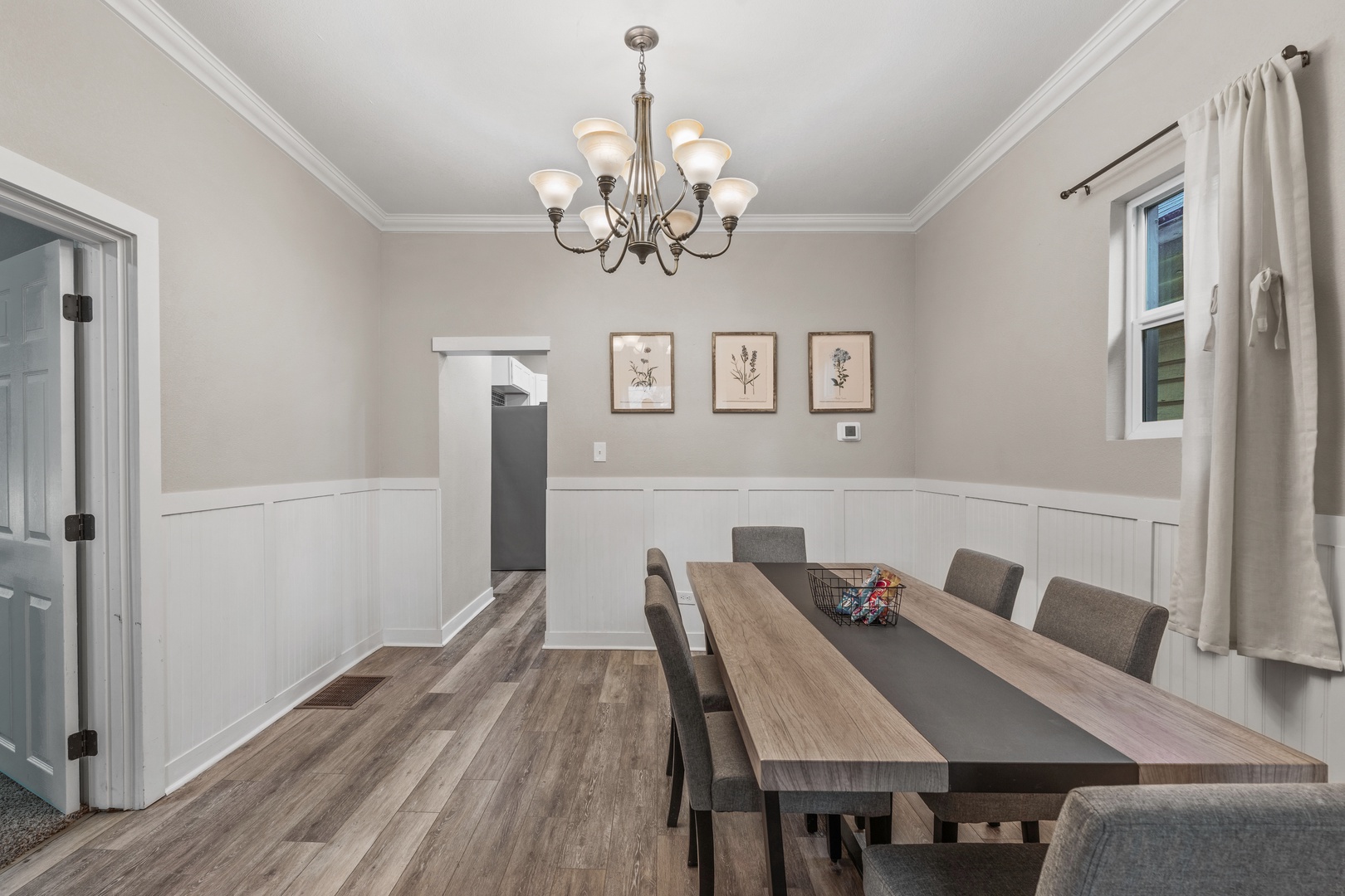 Gather around this elegant dining space featuring a spacious wooden table and sophisticated chandelier lighting for memorable meals with your group.