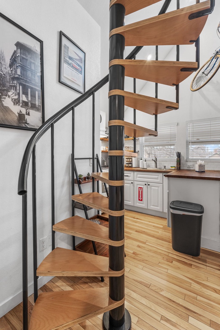 Ascend the modern spiral staircase to your loft space, where warm wood meets sleek design in your urban retreat.