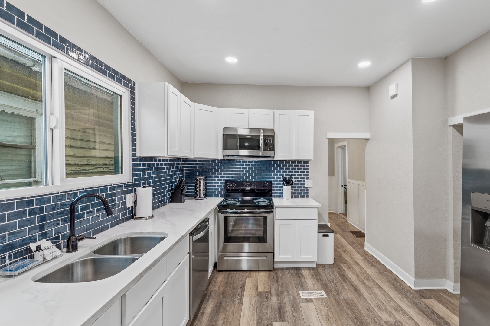 Your fully equipped kitchen features sleek white cabinets, stunning blue subway tile backsplash, and stainless steel appliances for all your culinary needs.