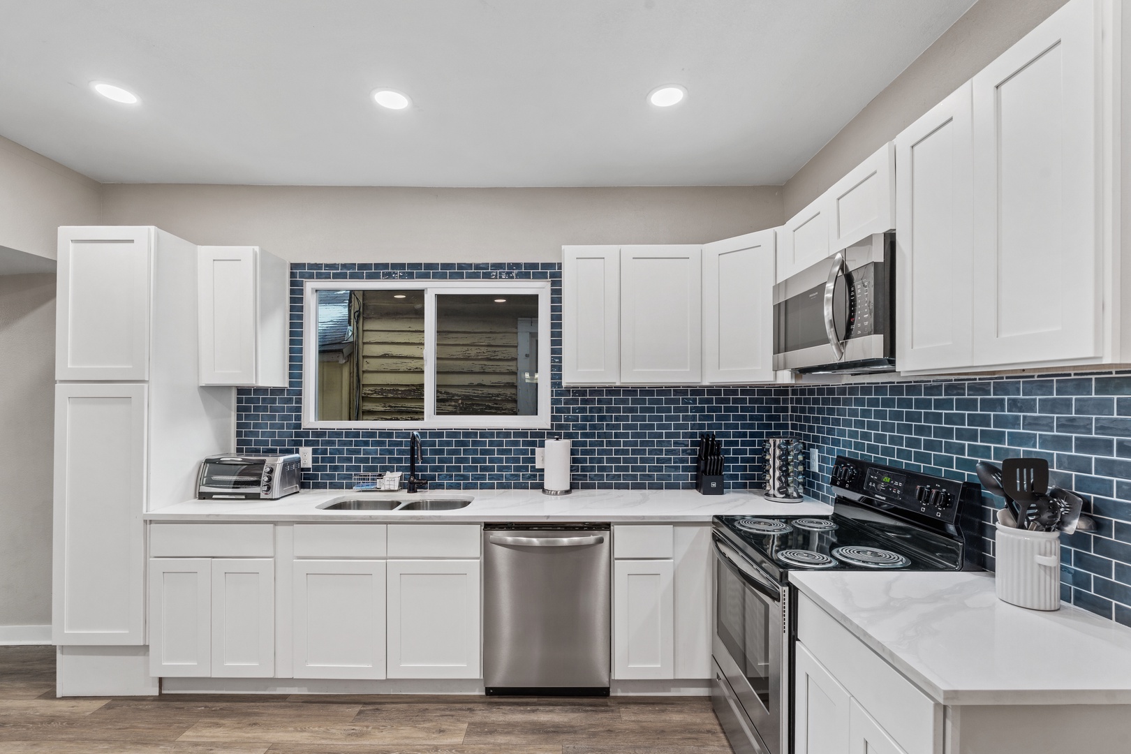 Your fully equipped kitchen features stainless steel appliances, white cabinets, and a stunning blue subway tile backsplash - perfect for preparing meals during your stay.