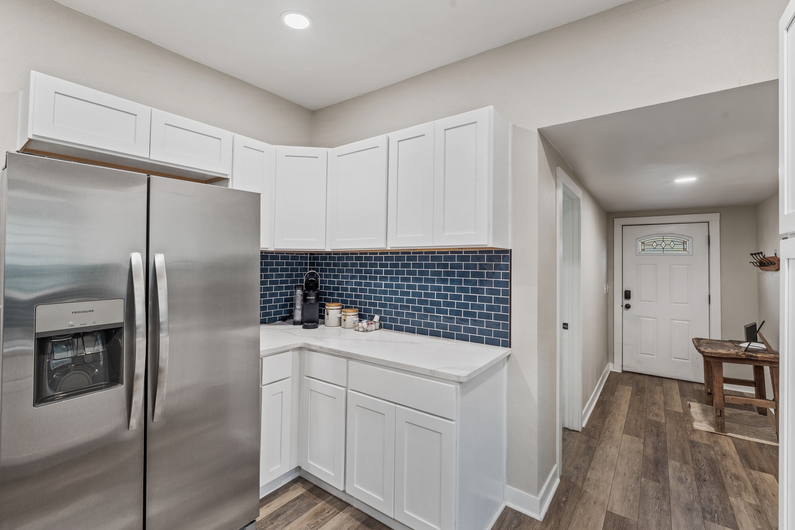 Your modern kitchen features crisp white cabinetry, stainless steel appliances, and a striking blue tile backsplash that adds character to your cooking space.