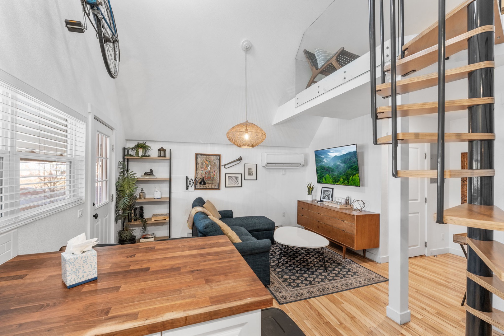 Relax in your modern loft with soaring ceilings, cozy seating, and unique spiral stairs leading to your private bedroom retreat above.