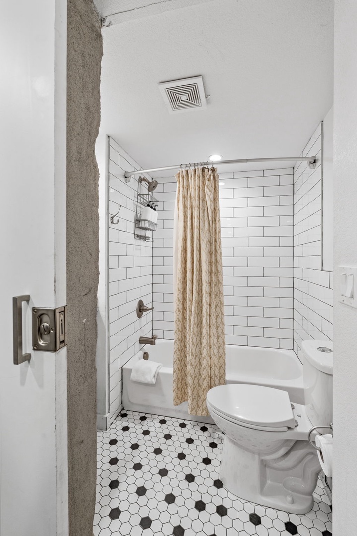 Your private bathroom features classic subway tiles, vintage hexagon flooring, and a refreshing tub-shower combo for relaxing after your adventures.