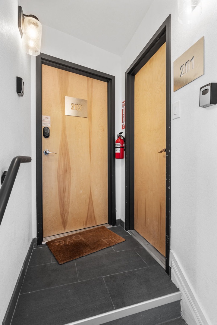 Modern hallway with clean white walls and dark tile flooring leading to numbered guest room doors.