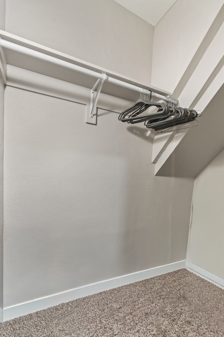 Your spacious walk-in closet features ample hanging space with convenient rod storage and hangers, perfect for organizing your wardrobe during your stay.