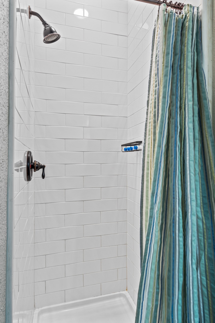Step into your private shower with classic subway tile walls and modern fixtures, complete with complimentary toiletries for your convenience.