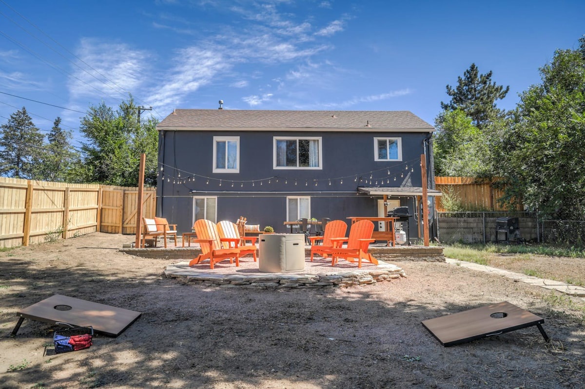 Modern two-story rental home with spacious backyard featuring bright orange Adirondack chairs and fire pit for memorable evenings.